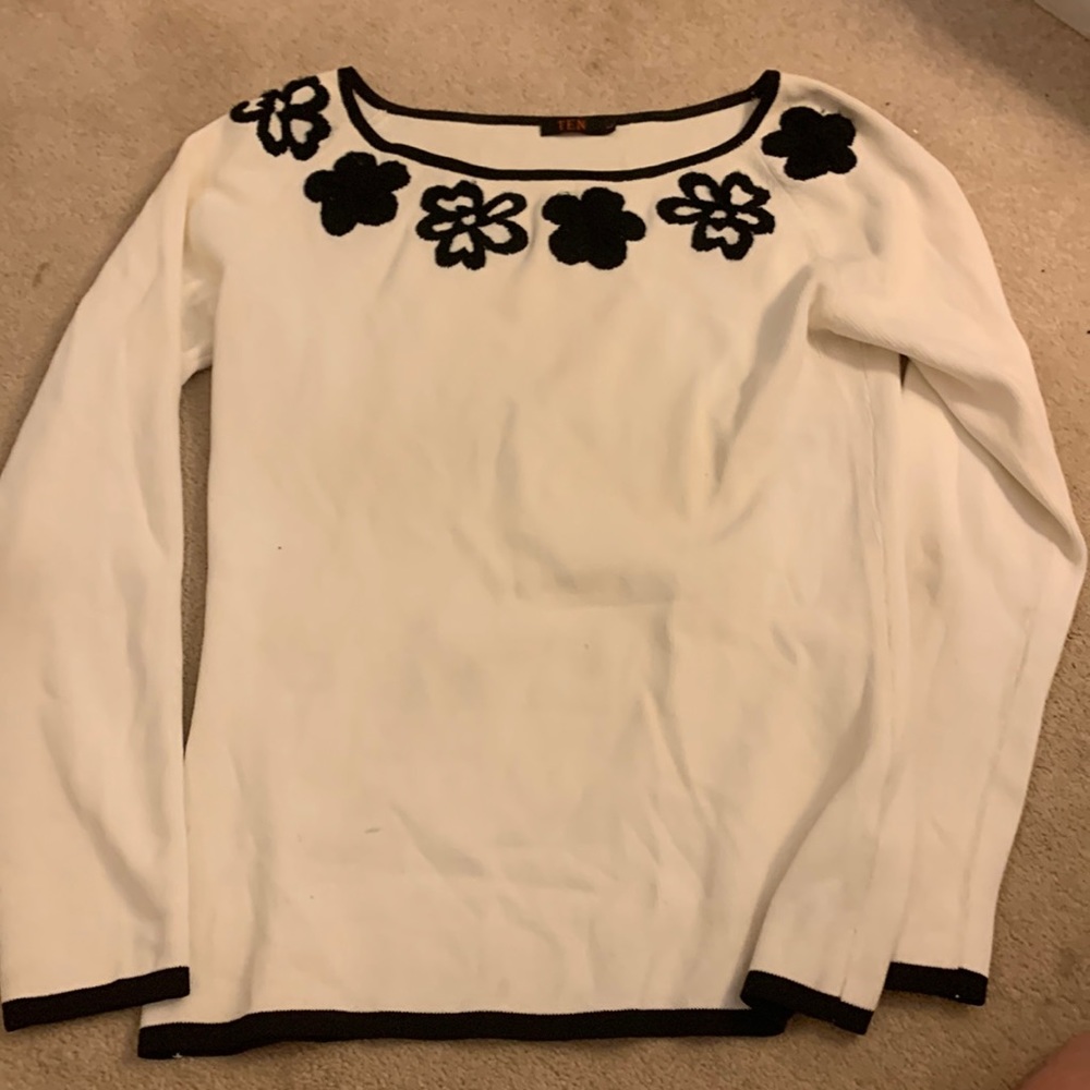 Ten white sweater with black flowers around collar